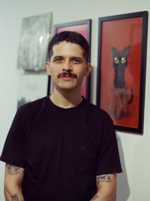 Scanned film photograph of a person (a man with short black hair and a mustache wearing a black t-shirt) looking at the camera.